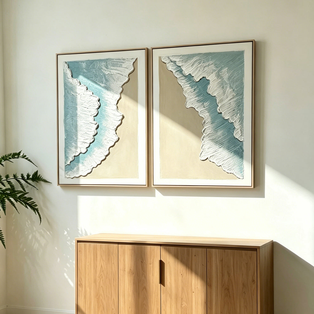 Shoreline diptych in pale wood frames above an oak cabinet in a sunlit room