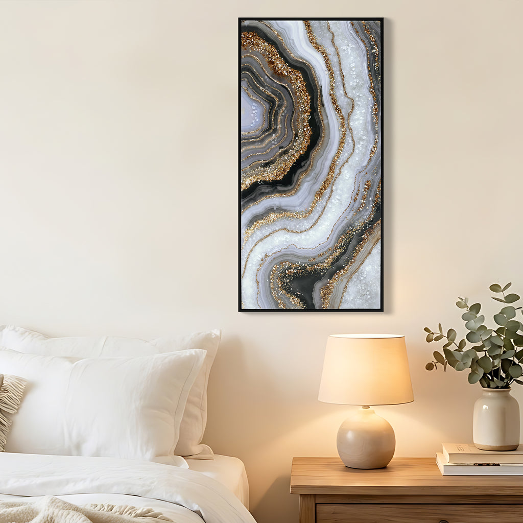 Geode canvas in a black frame hung beside a bed with a warm lamp